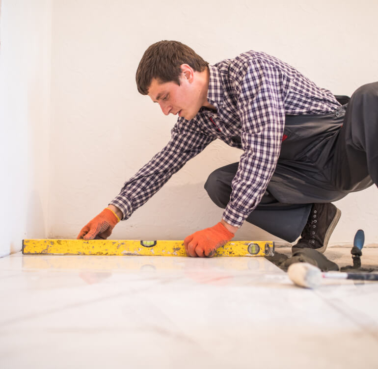 Installer levelling ceramic floor tile with a spirit level