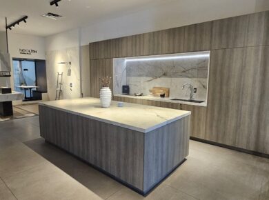 Kitchen showroom display with grey wood-grain cabinets and a sintered-stone island