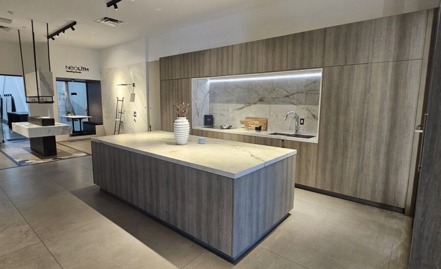 Kitchen showroom display with grey wood-grain cabinets and a sintered-stone island