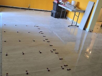 Large-format porcelain floor tile being laid with spacers during a condo remodel