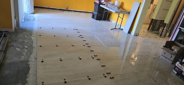 Large-format porcelain floor tile being laid with spacers during a condo remodel