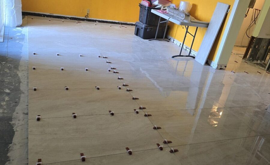 Large-format porcelain floor tile being laid with spacers during a condo remodel
