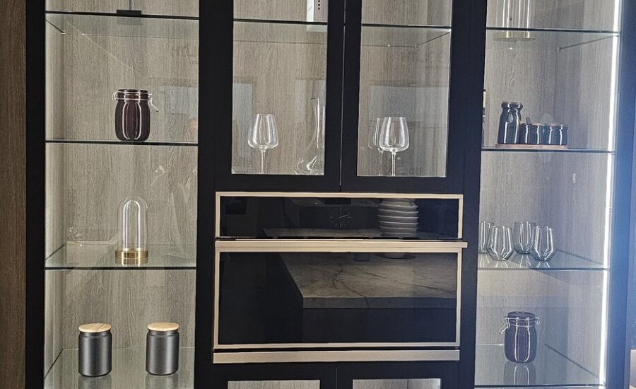 Showroom display of tall black-framed glass-front cabinets with lit glass shelves