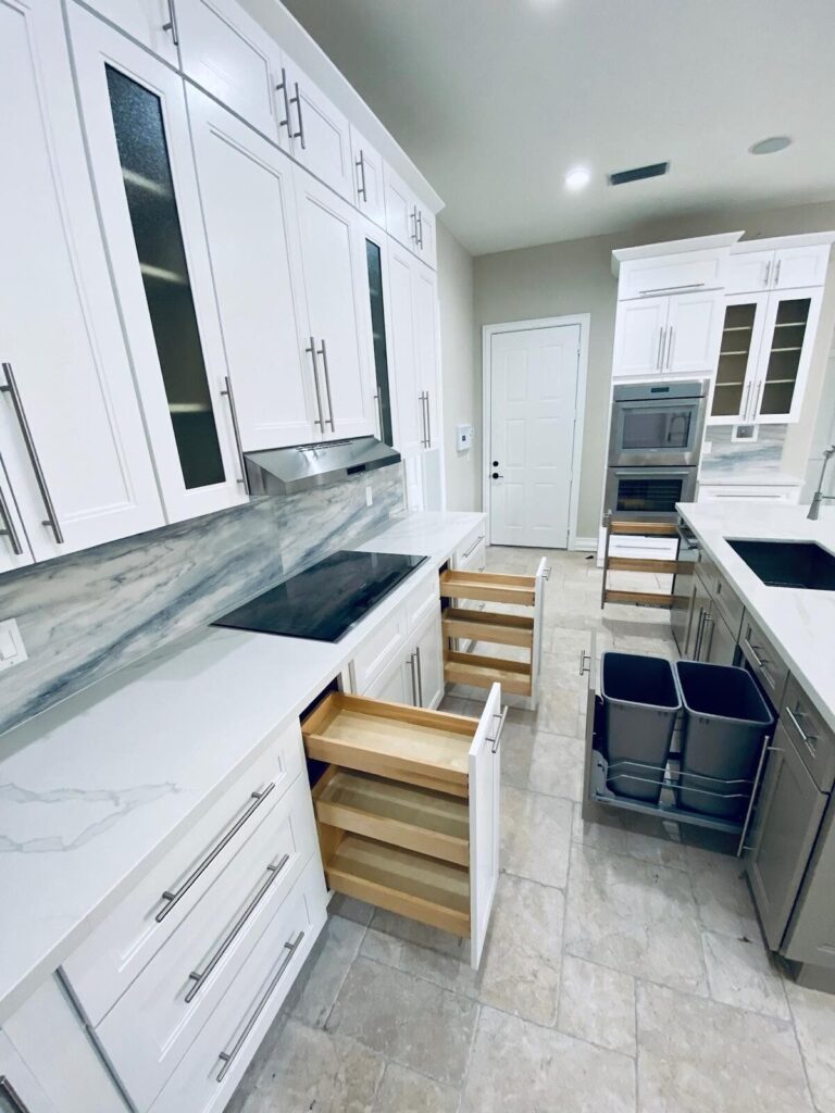White shaker cabinets with a pull-out spice rack and a double trash pull-out, built and installed by Dreamery