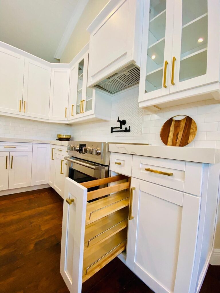 Custom white shaker cabinets with a deep pull-out drawer and brass pulls, built and installed by Dreamery
