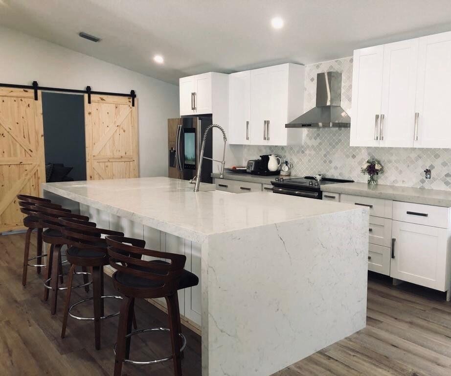 White shaker kitchen with a waterfall island and barn doors, built and installed by Dreamery
