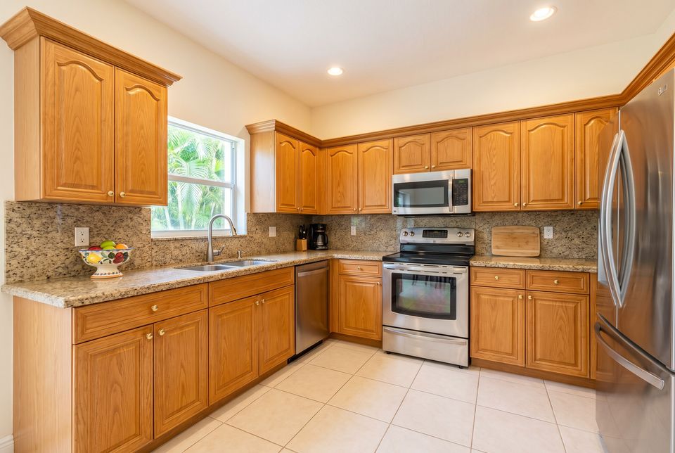 Before: a 1990s South Florida kitchen with honey-oak raised-panel doors and small brass knobs