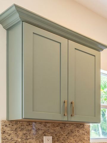 Sage green shaker wall cabinet with aged brass bar pulls