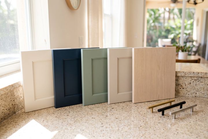 Cabinet door samples in white, navy, sage, greige and light oak, with brass, black and nickel bar pulls