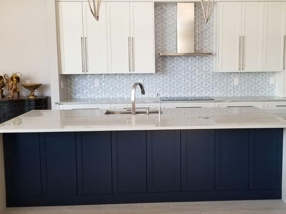 Before: a white shaker kitchen with a navy island, a white quartz waterfall top and a geometric tile backsplash